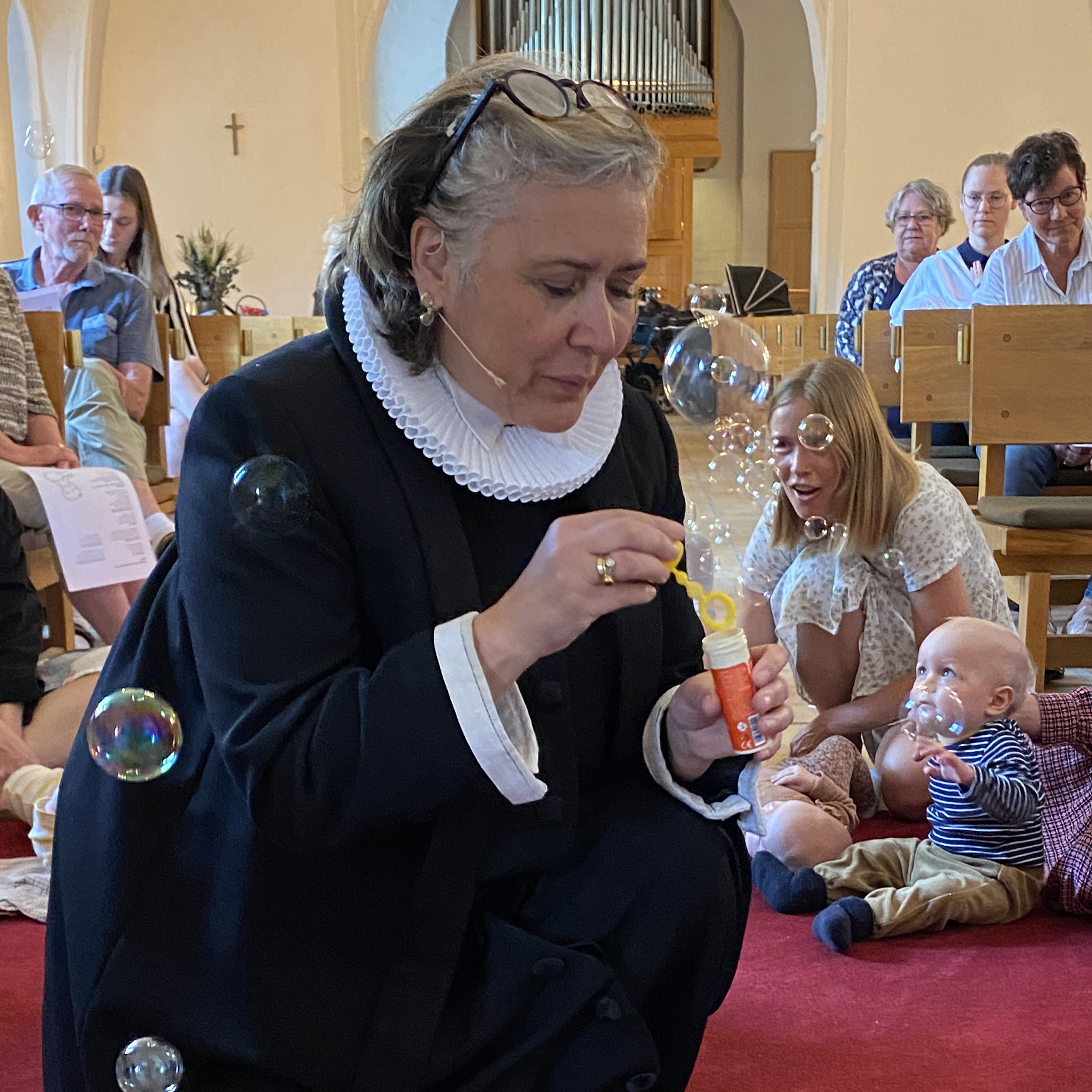 Præst Mia Lund Rao blæser sæbebobler til børnegudstjeneste