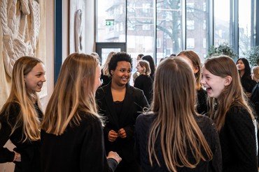 Pigerne fra Pigekoret snakker i små grupper i salen i Sognehuset